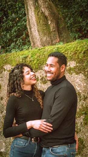 A smiling couple embraces each other outdoors.