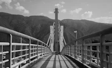 A bridge leads to tower in front of mountains.