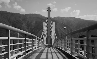 A bridge leads to tower in front of mountains.