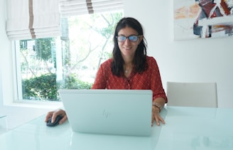 Woman smiles while working on a laptop.