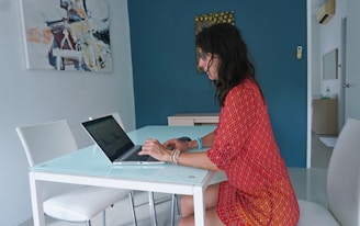 Woman works on laptop at a table.