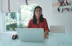 Woman works on laptop at a bright, modern table.