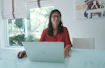 Woman works on laptop at a bright, modern table.