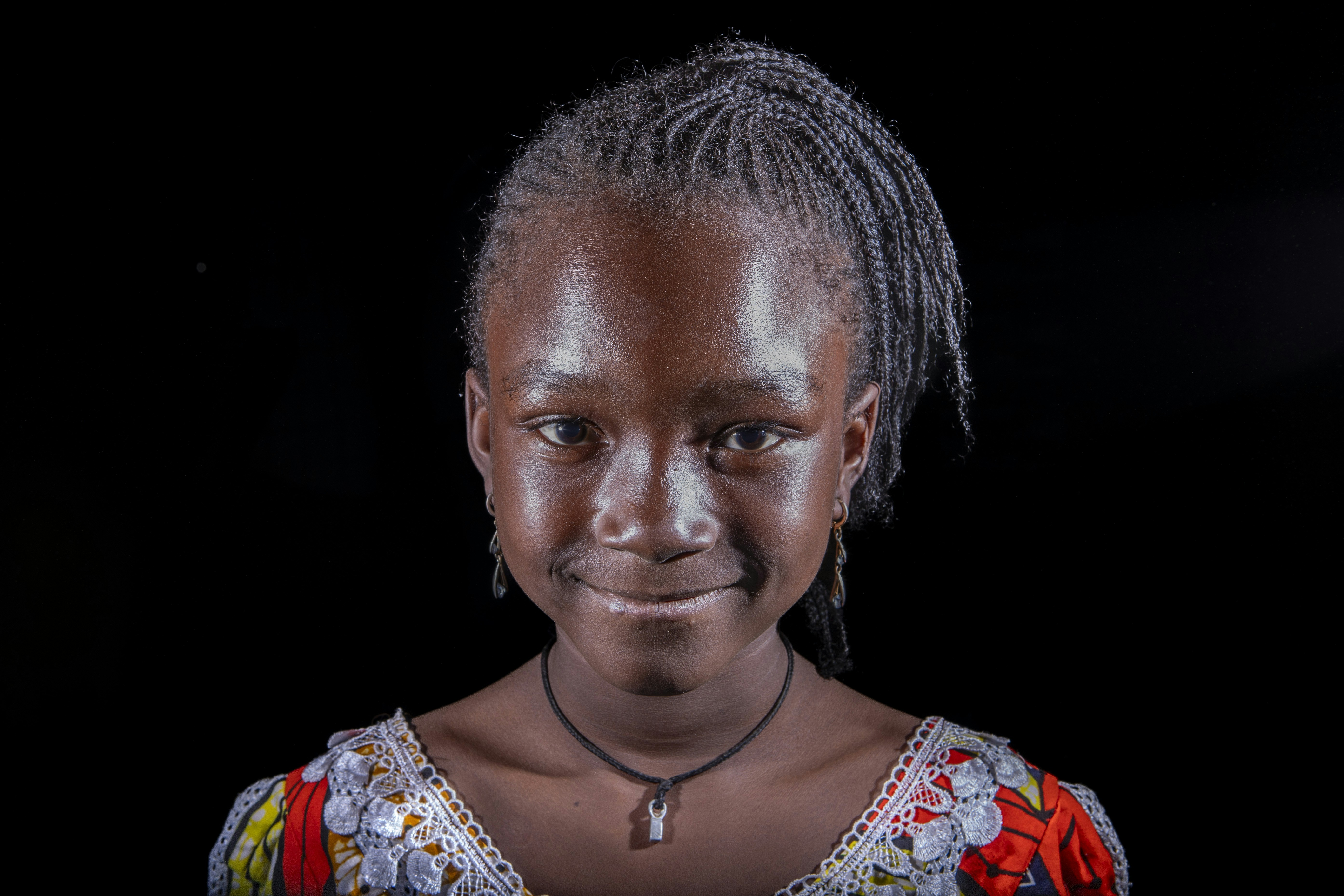 A young african girl smiles brightly for the camera.