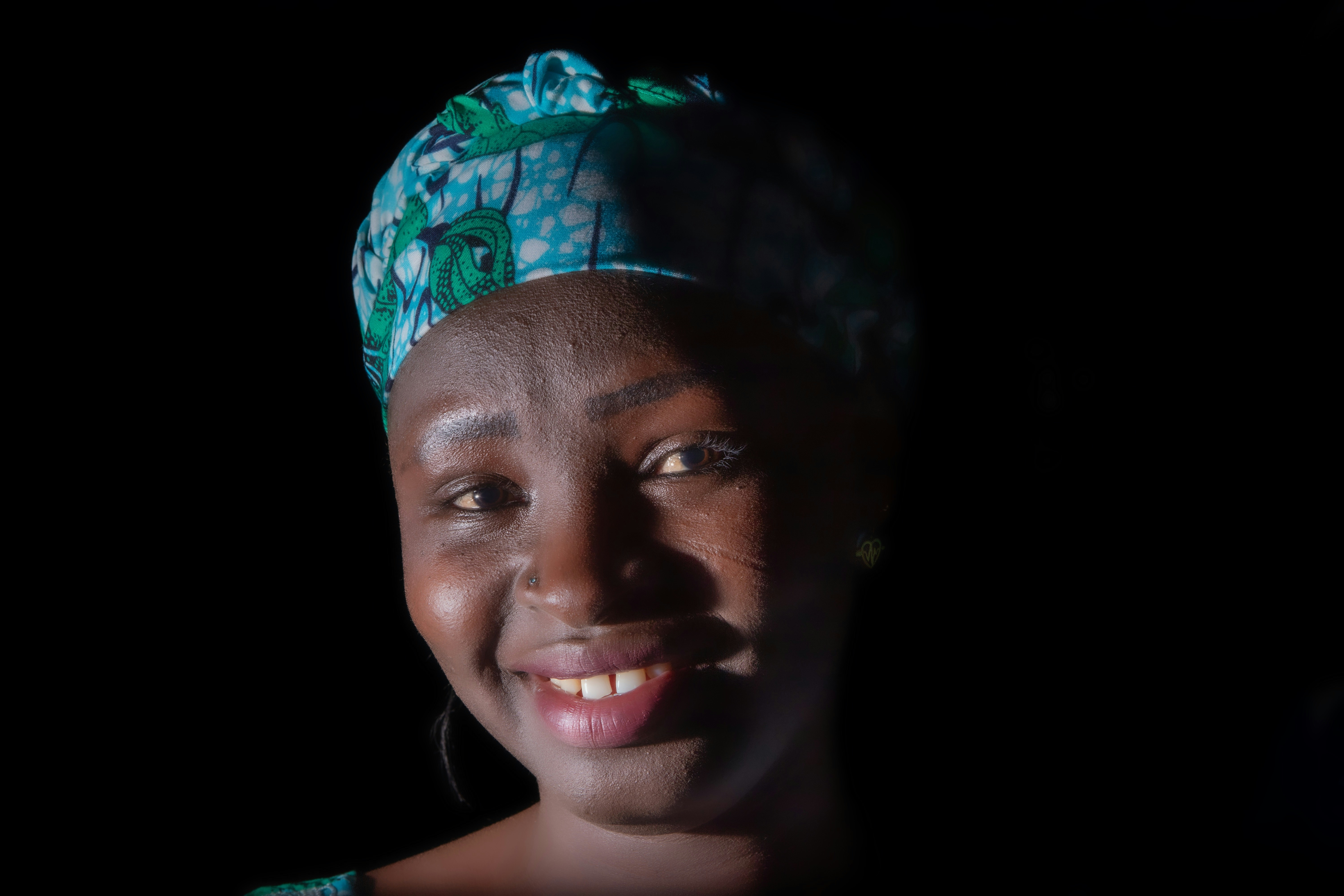 Smiling woman with a patterned headscarf.
