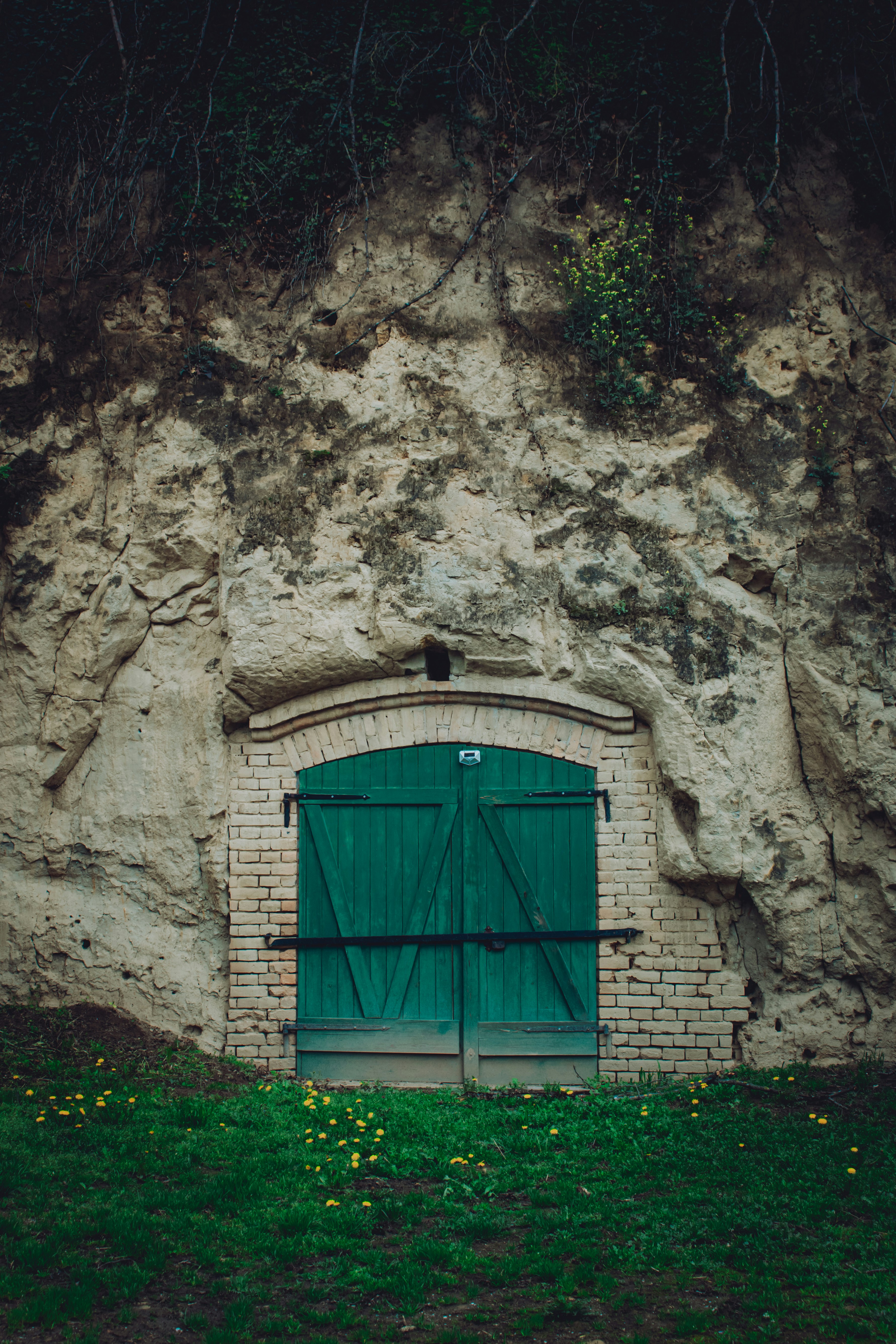 Green doors lead into a stone cave.
