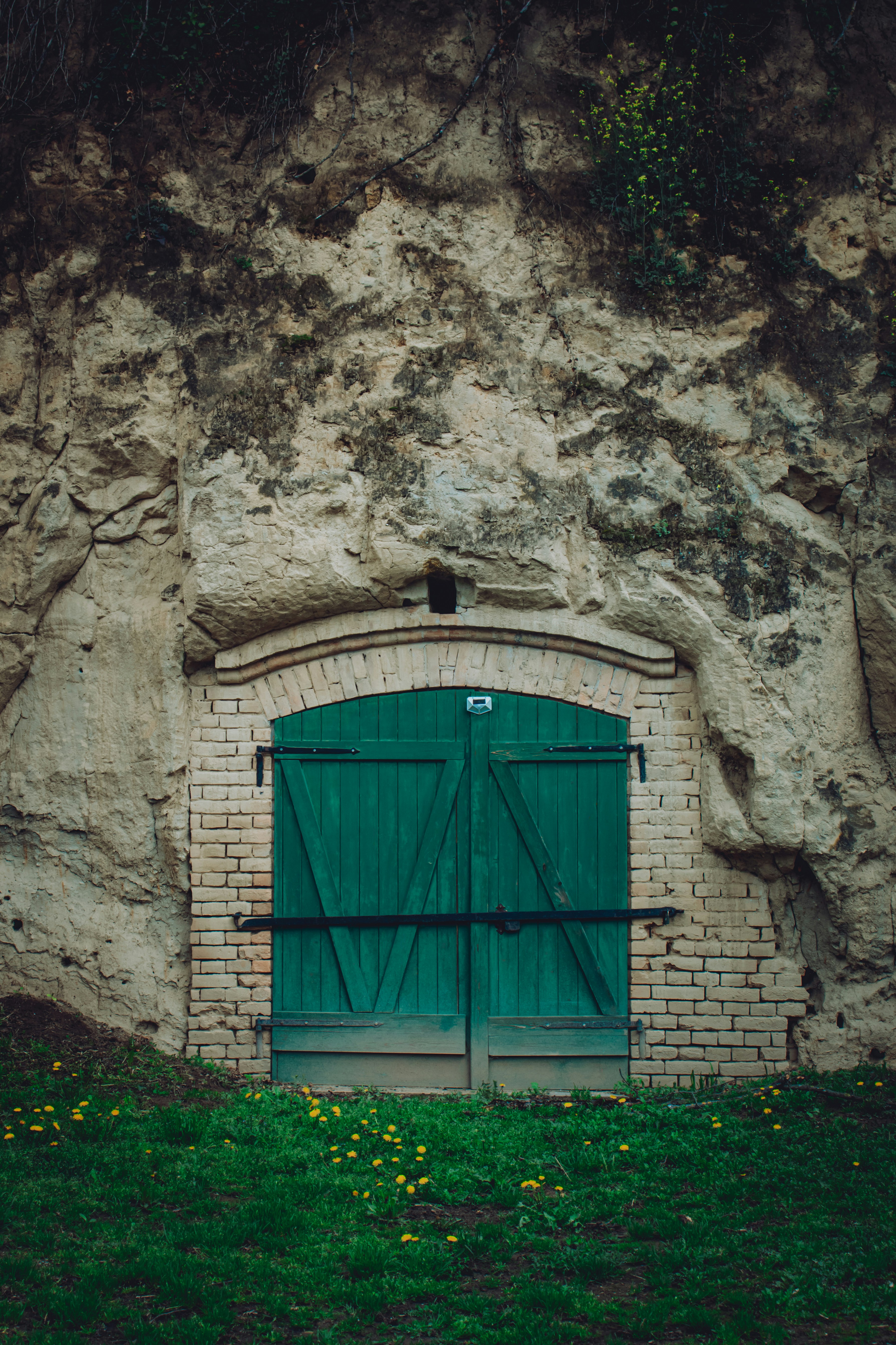 A green door enters a rock cliff.