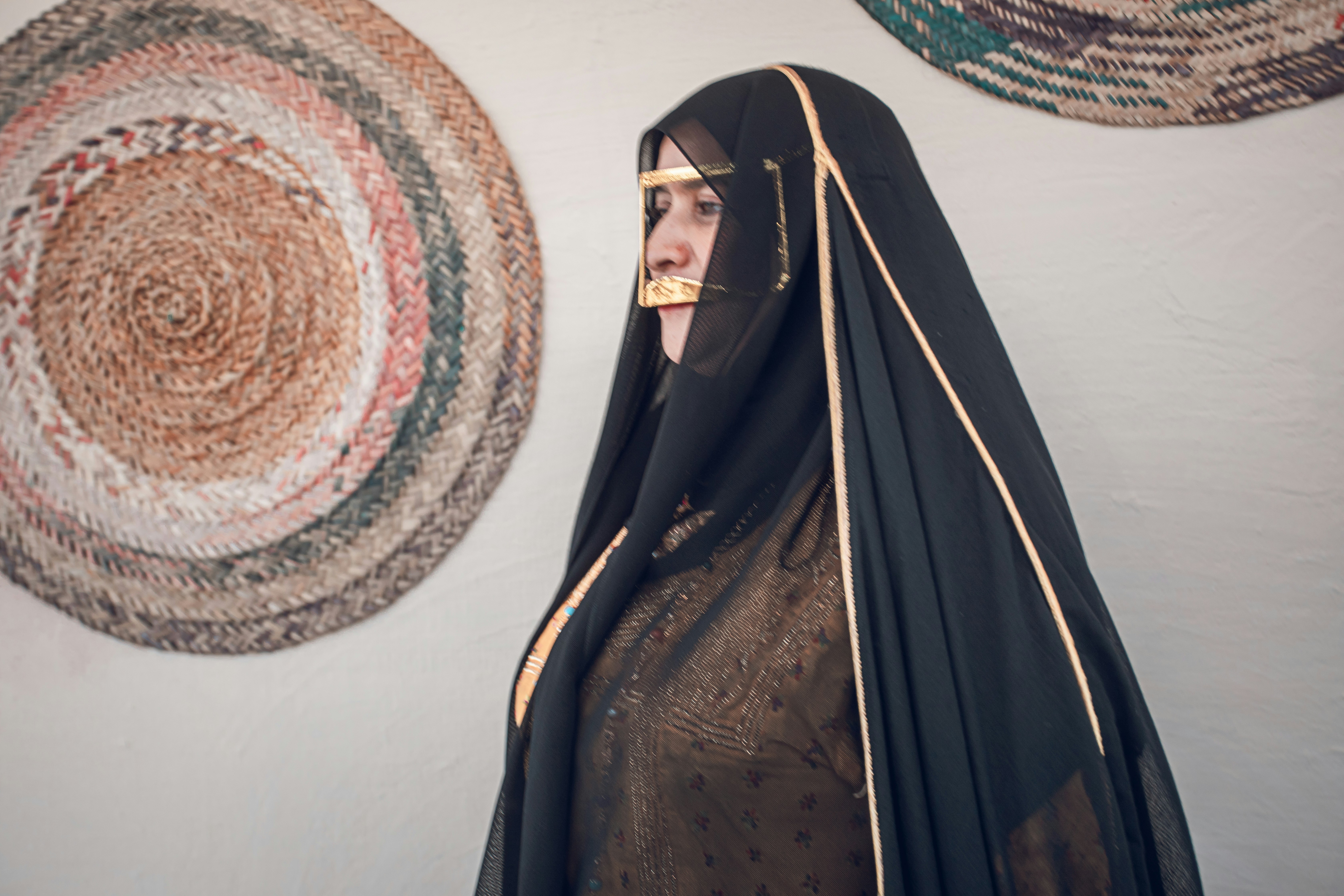 Wanita berpakaian tradisional dengan seni dinding dekoratif.