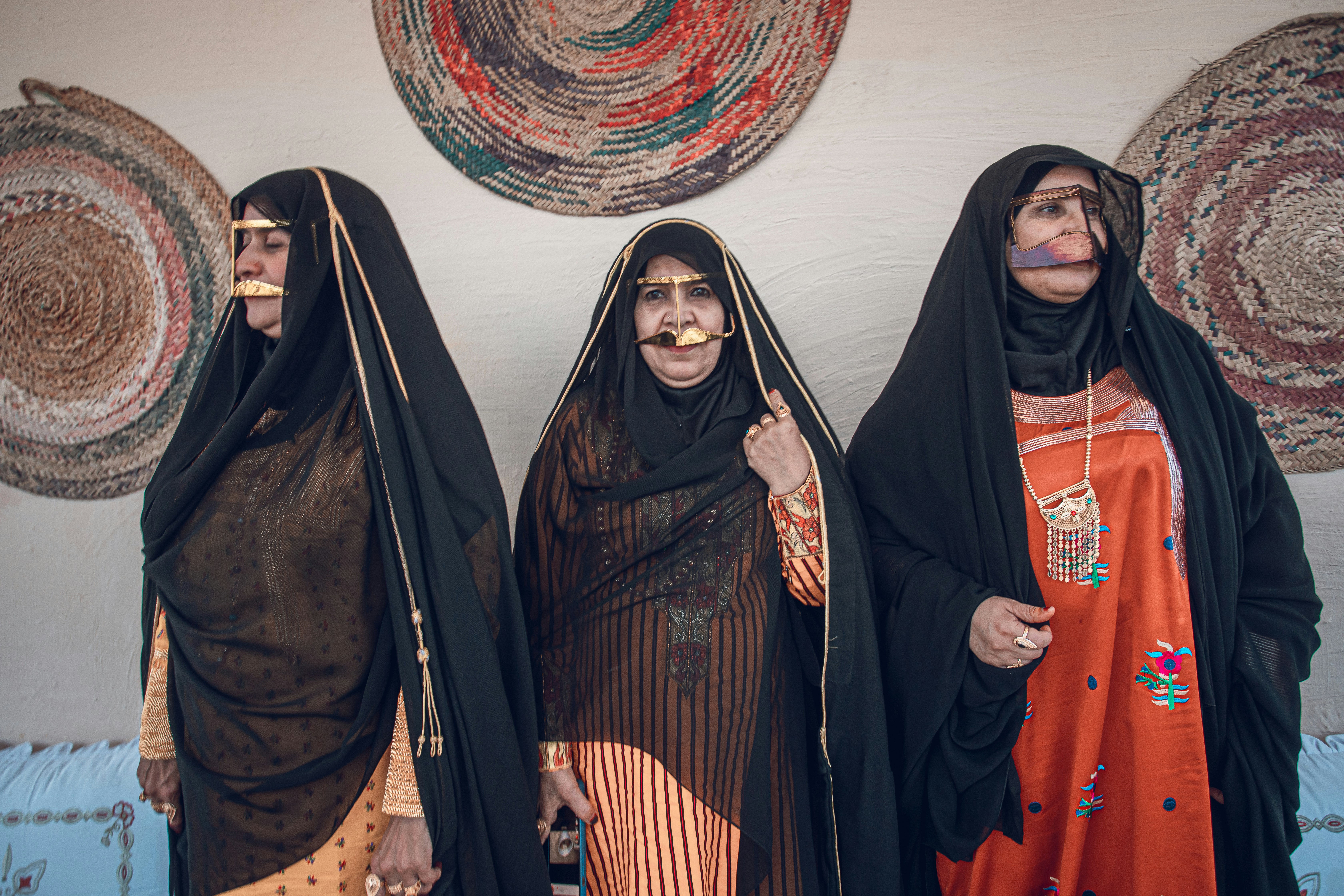 Three women in traditional attire stand together.