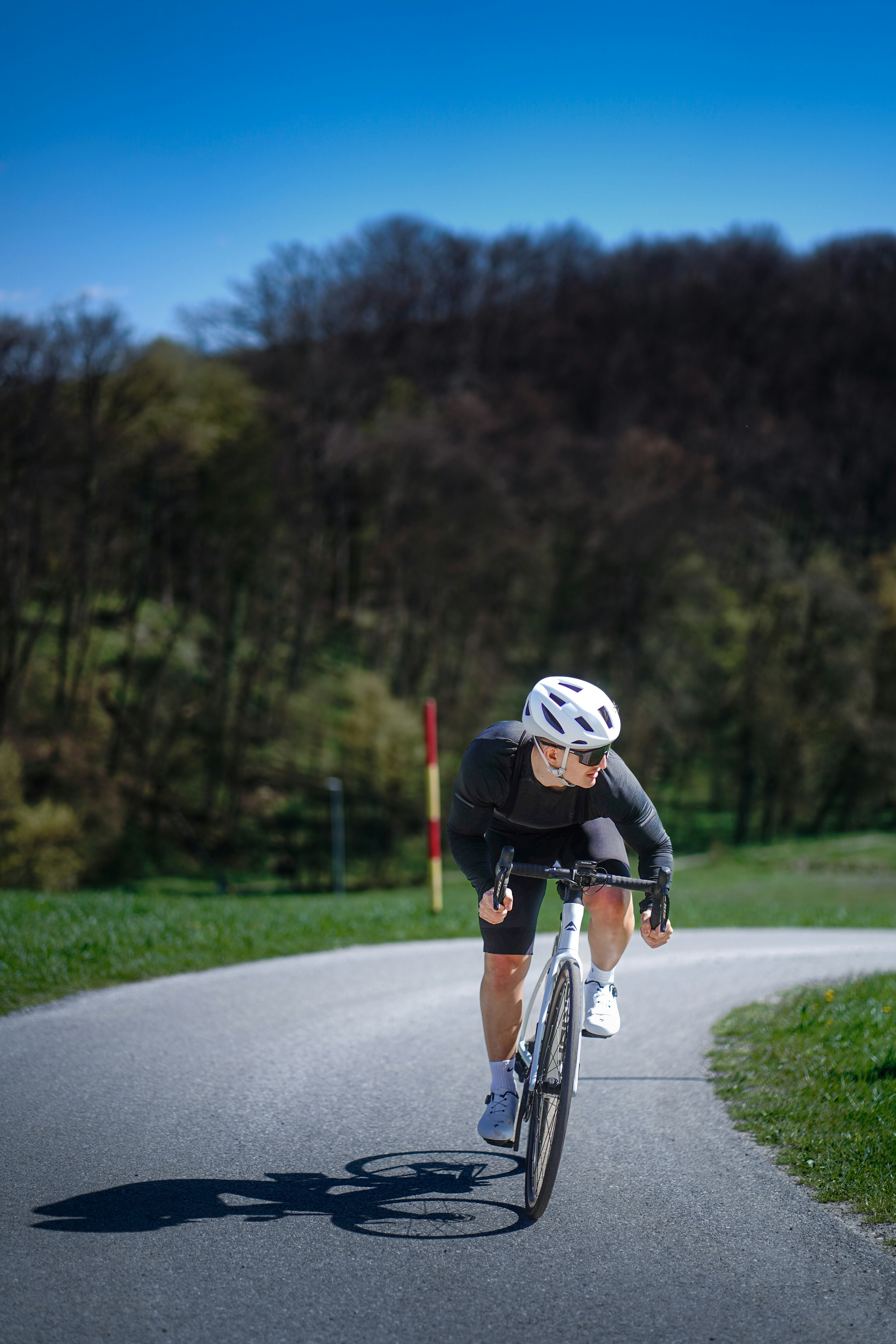 Cyclist rides on a winding road outdoors.