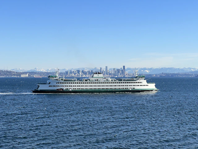 A ferry sails across the water with a skyline view.