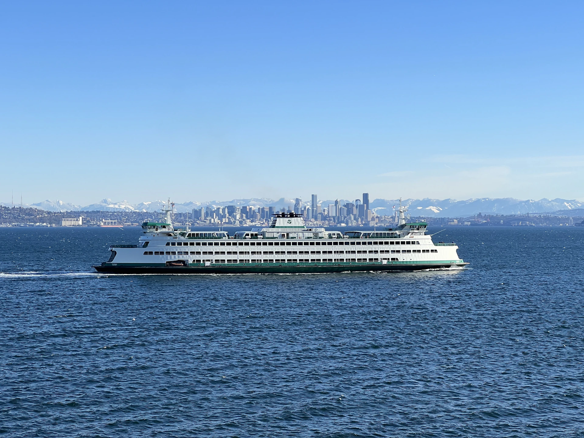 A ferry sails across the water with a skyline view.
