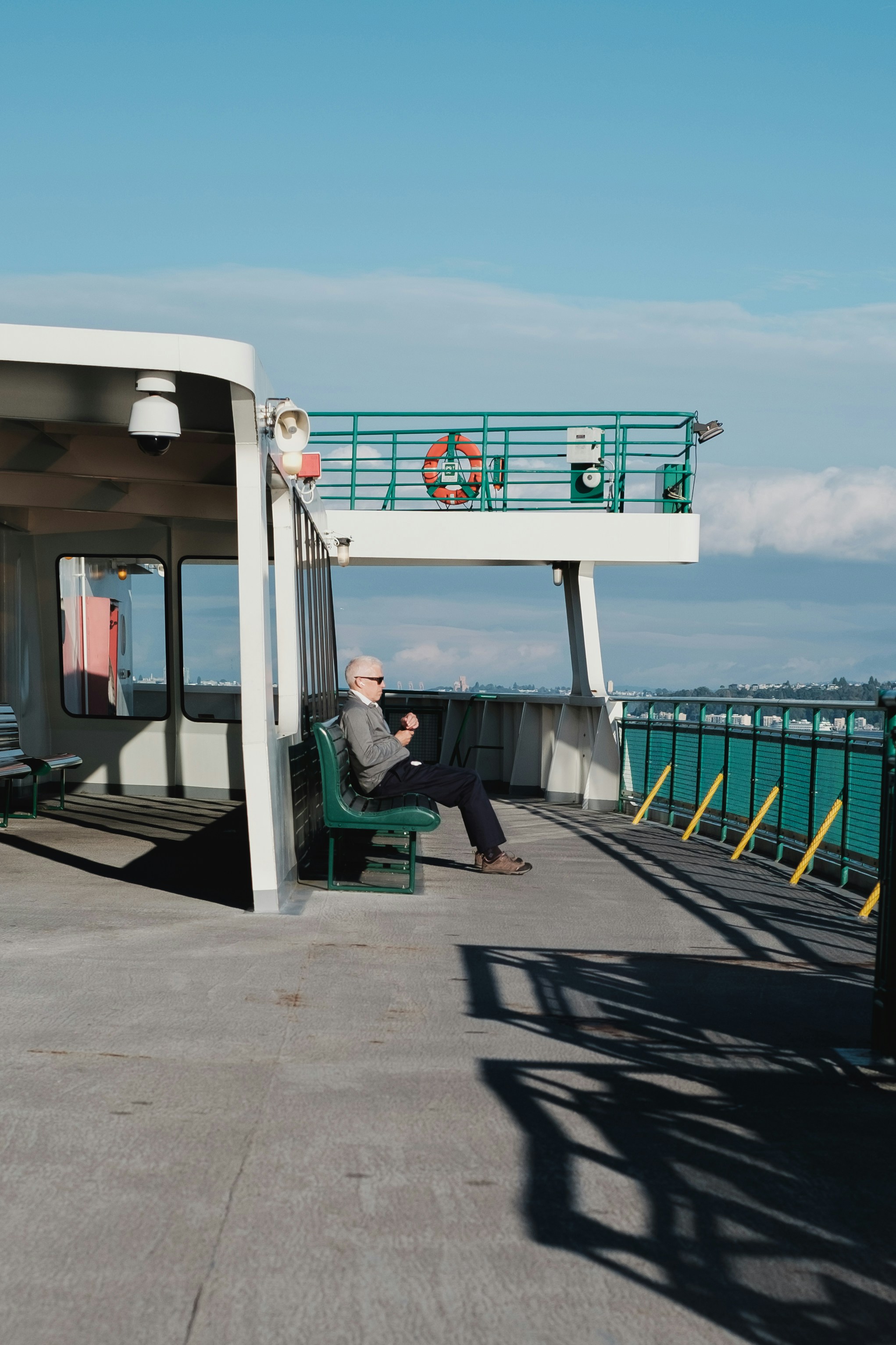 A man sits on a ferry, enjoying the views.