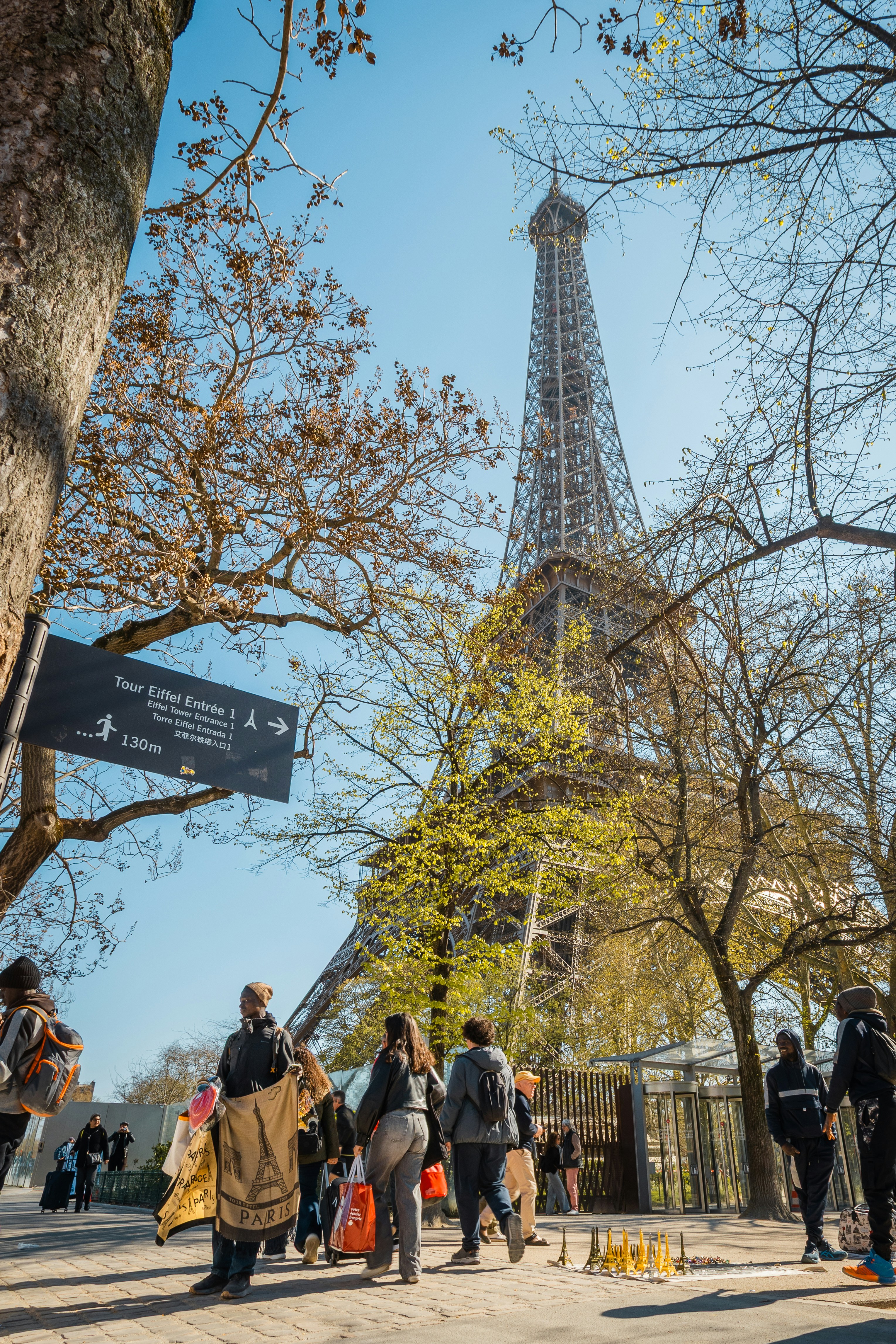 People walk near the eiffel tower on a sunny day