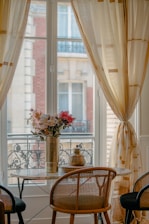 A window with flowers and a table.