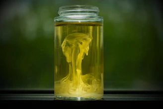Yellow substance swirls inside a glass jar.