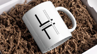 A white mug with a design is in a box.