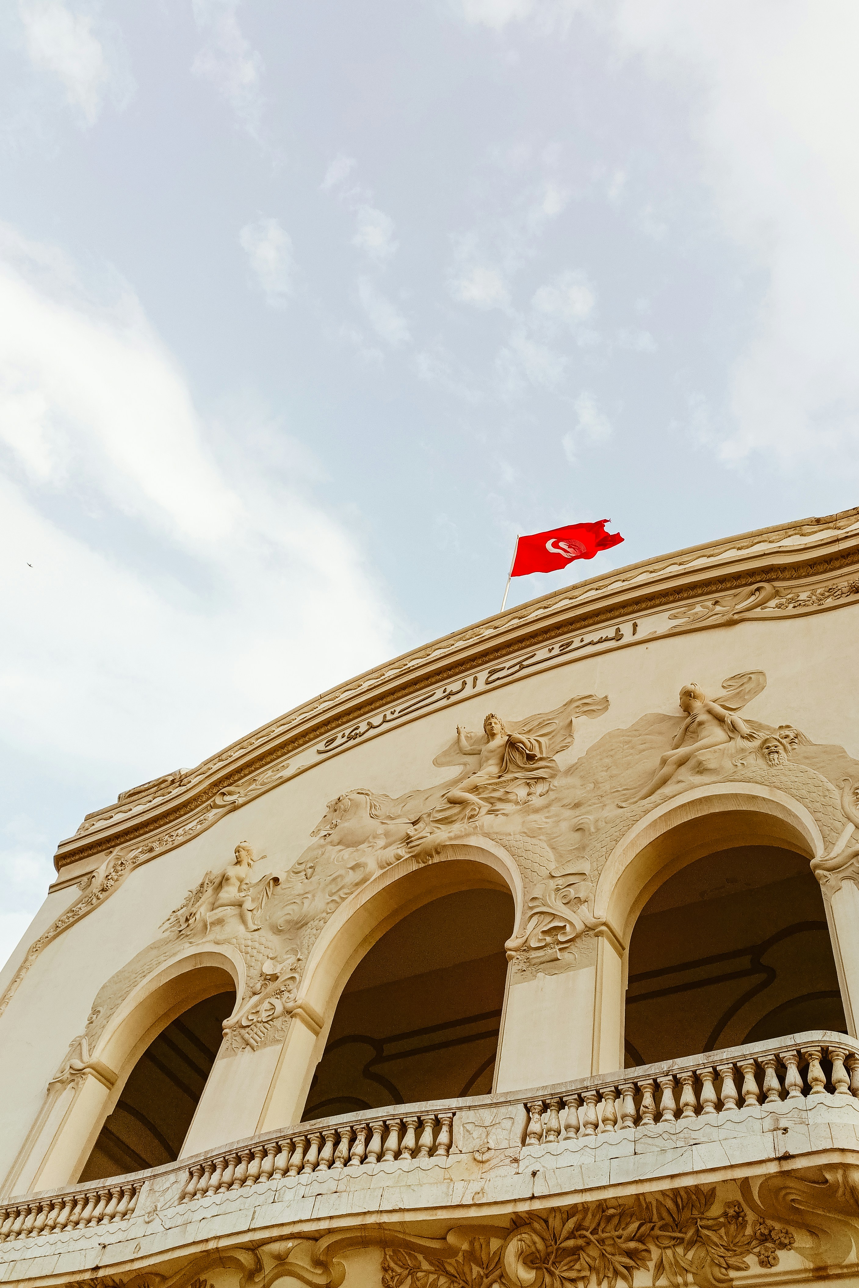 The tunisian flag flies above a decorated building.