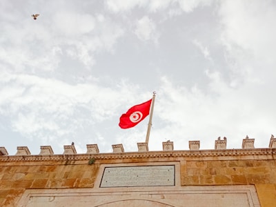 The tunisian flag waves proudly in the sky.