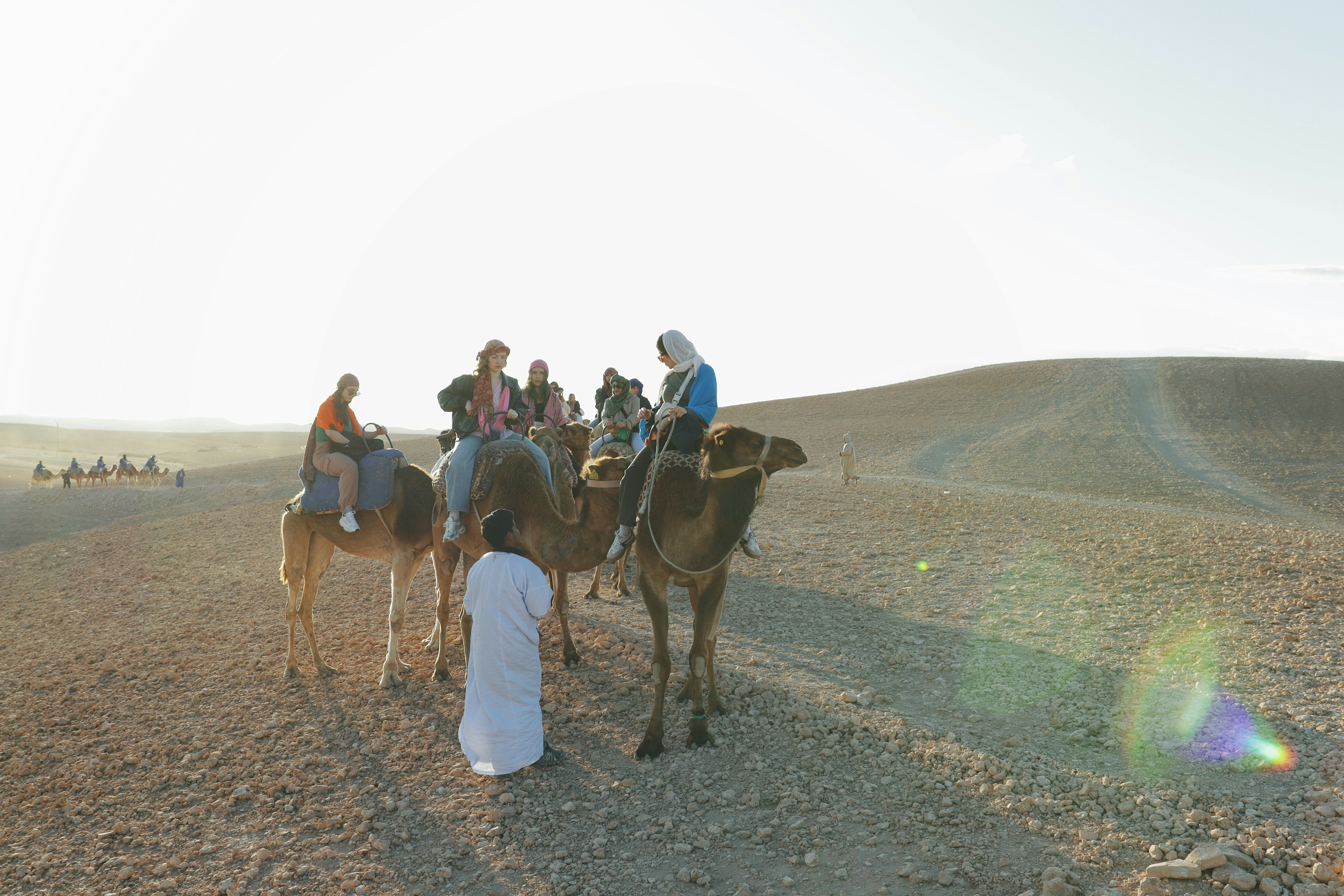 People riding camels in the desert landscape.