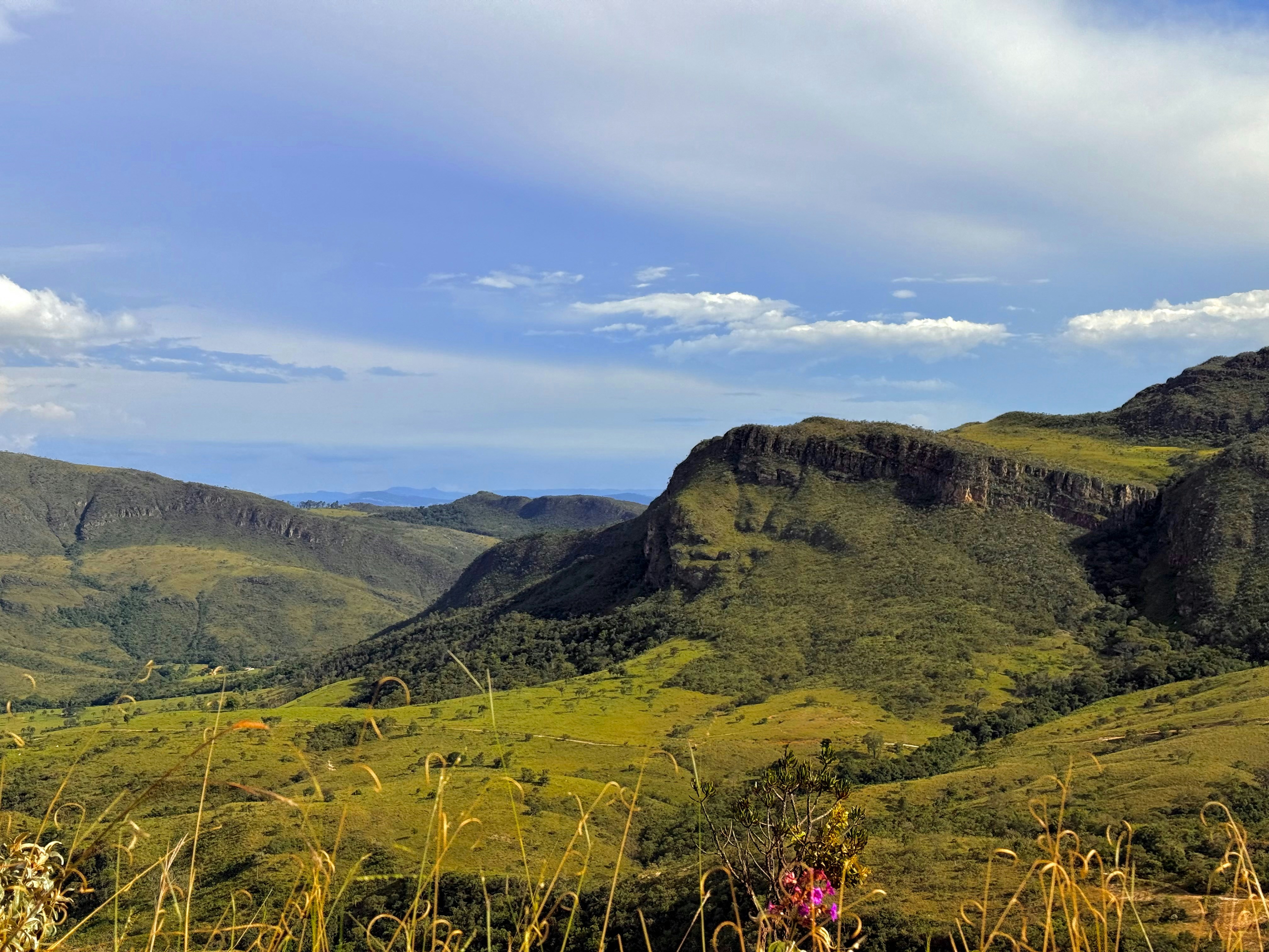 Mountains and valleys stretch under a cloudy blue sky.