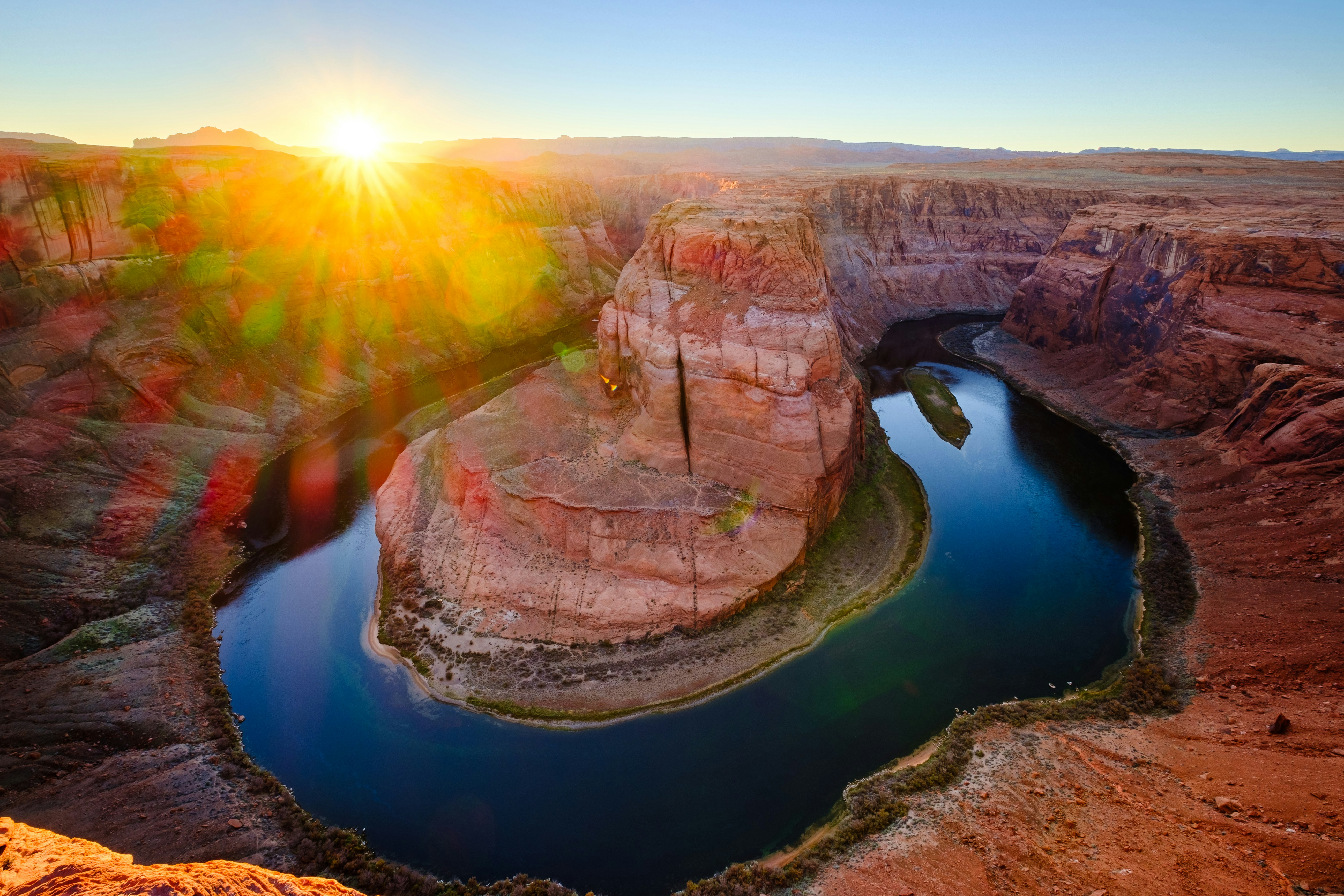 The sun shines over horseshoe bend's river.