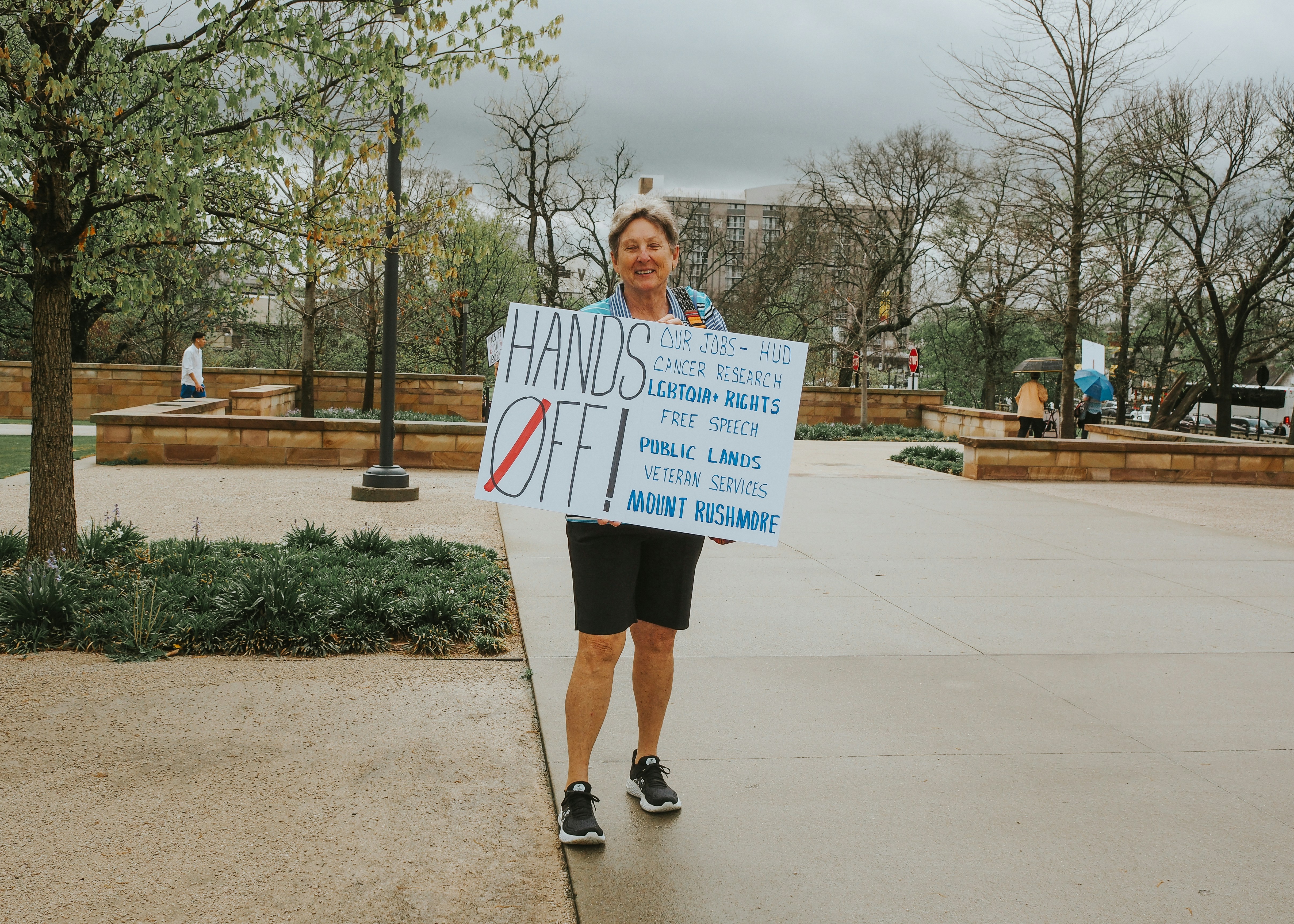 Woman protests with a sign reading "hands off!"