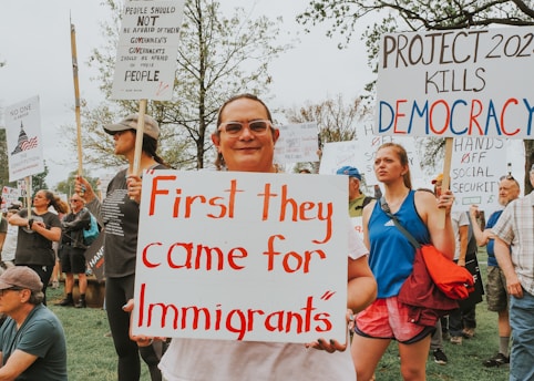 Protesters hold signs about immigrants and democracy.