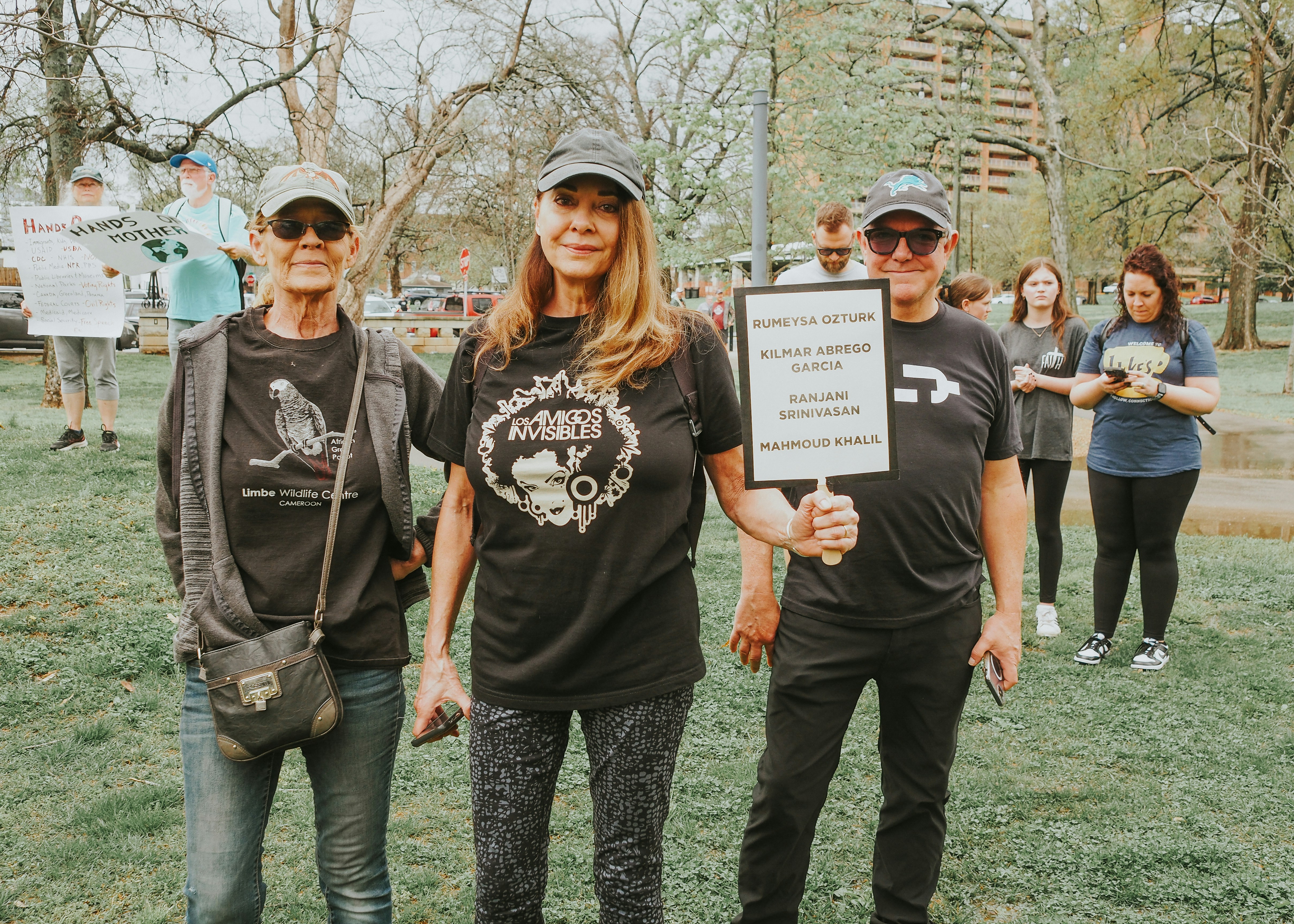 People are holding signs at an outdoor protest.