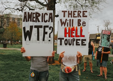 Protesters hold signs with political statements.