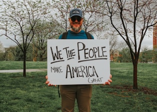 Man holds a sign: "we the people make america great."