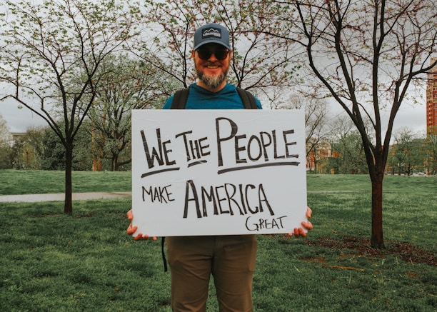 Man holds a sign: "we the people make america great."