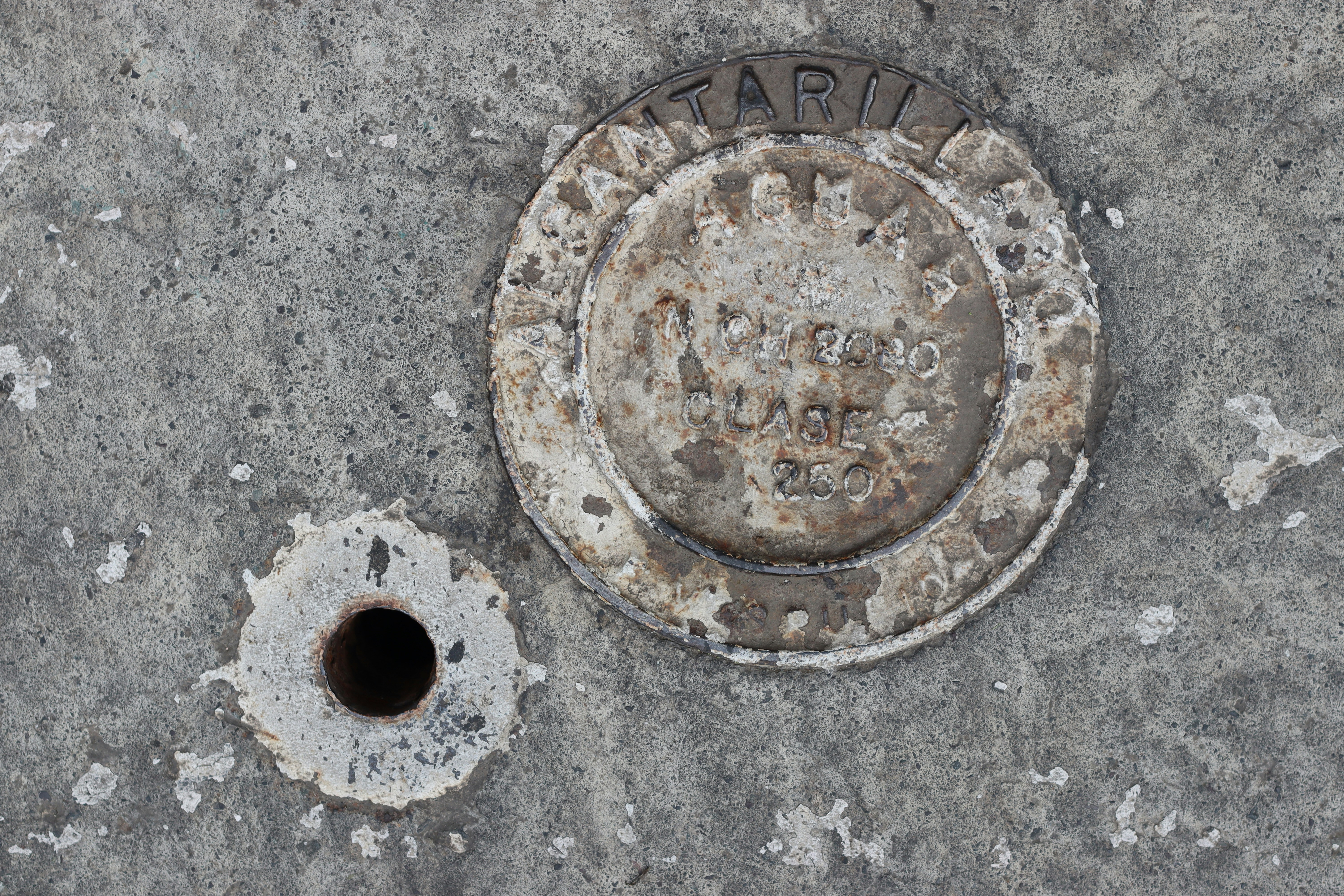 A marker and hole are on concrete.