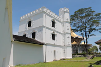 A white tower building stands tall under a blue sky.