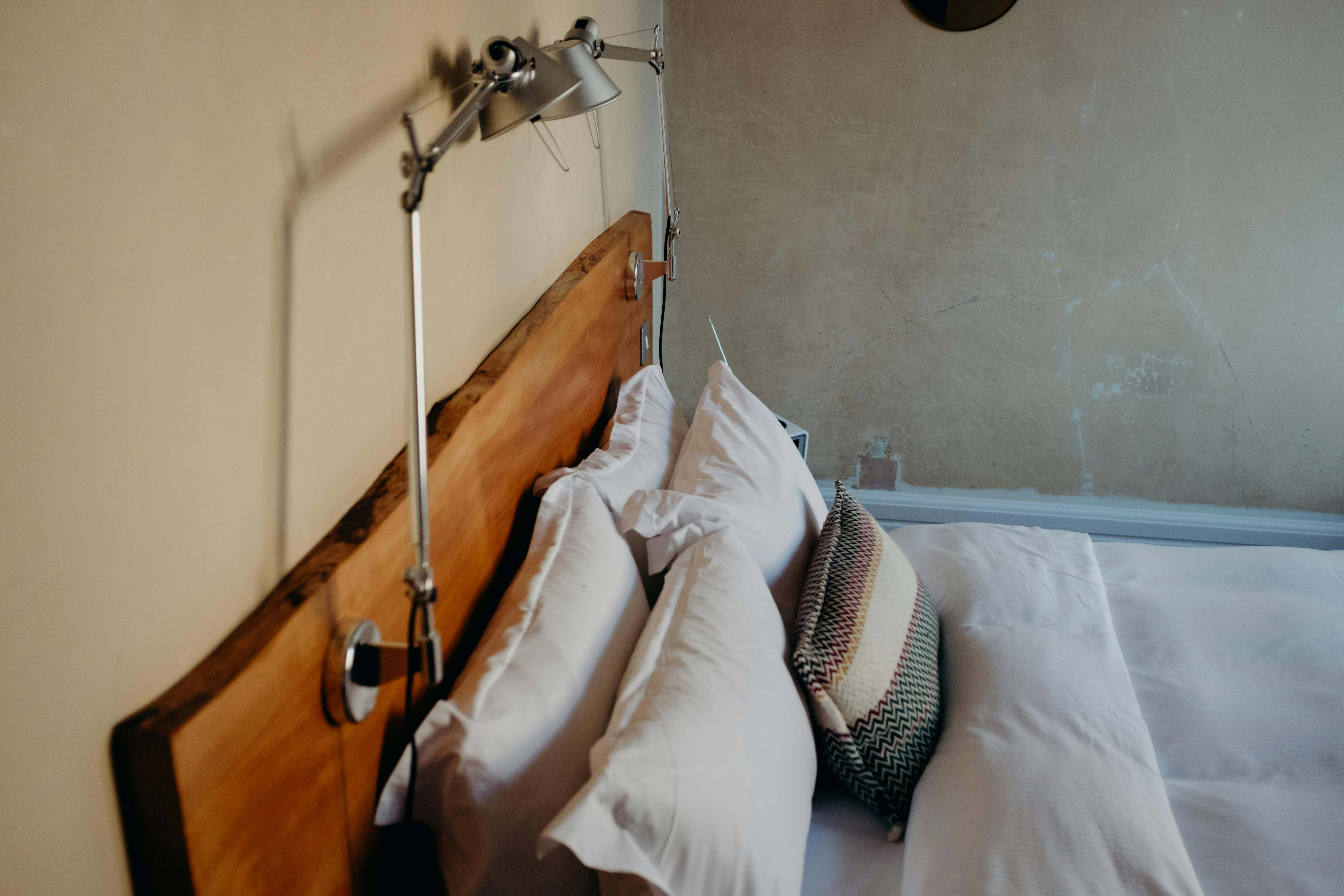 A bed with pillows and a reading lamp.