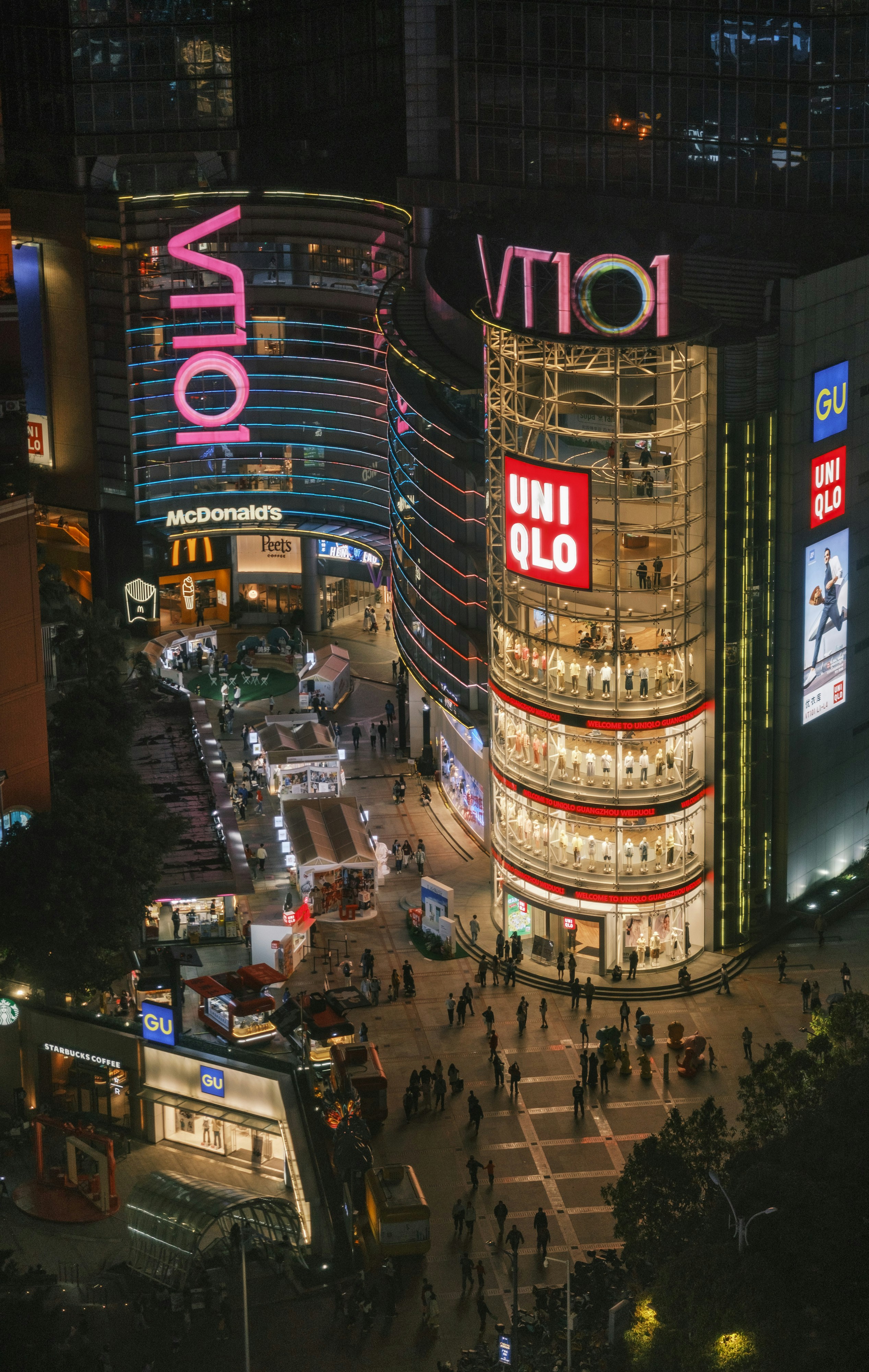 Nighttime view of a busy street with illuminated shops.