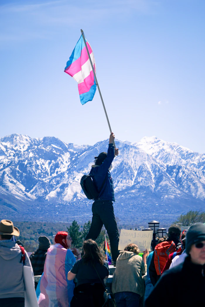 Una persona sostiene la bandera trans al aire libre.