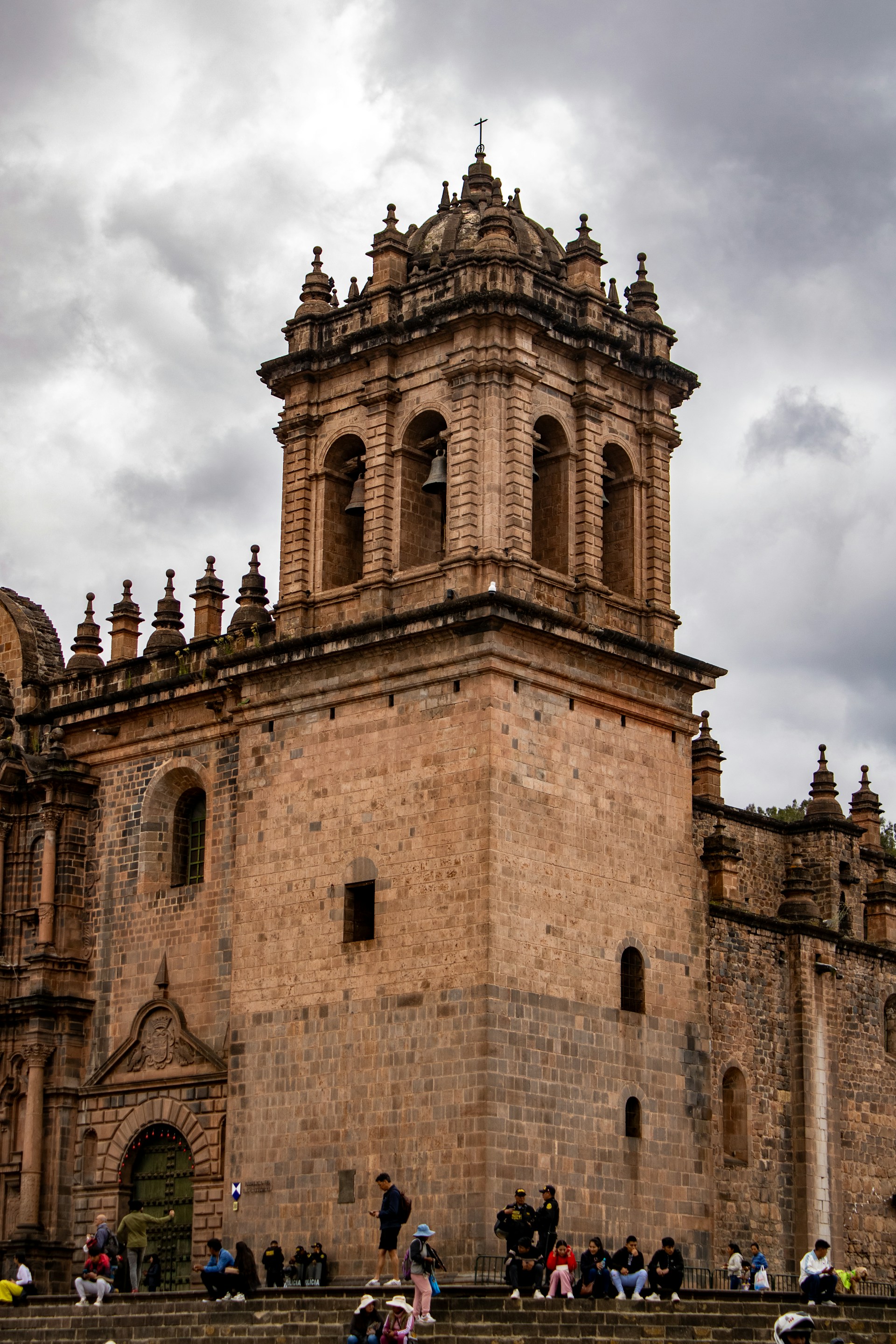 A stone church tower stands tall against the cloudy sky.