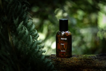 A perfume bottle sits against a nature backdrop.