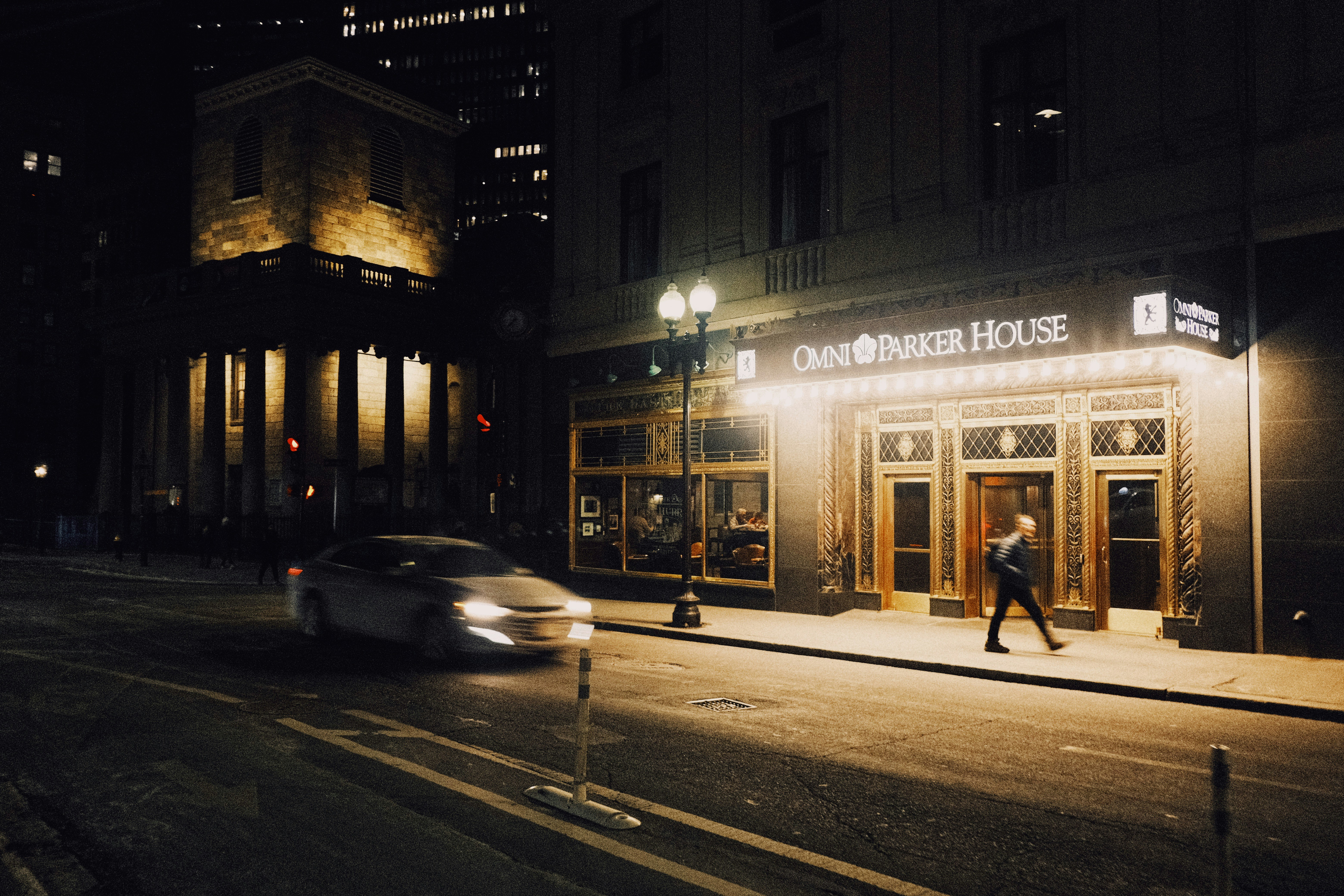 A man walks past a lit-up building at night.