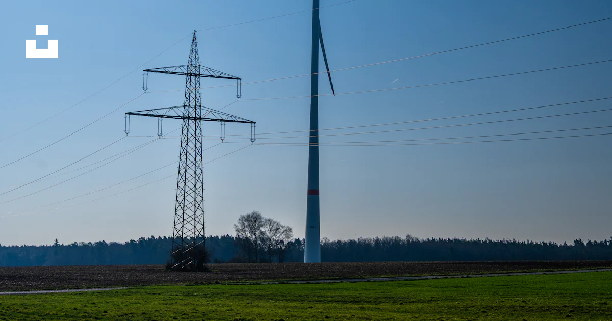 Wind turbine and power line stand tall in the field. photo – Free ...