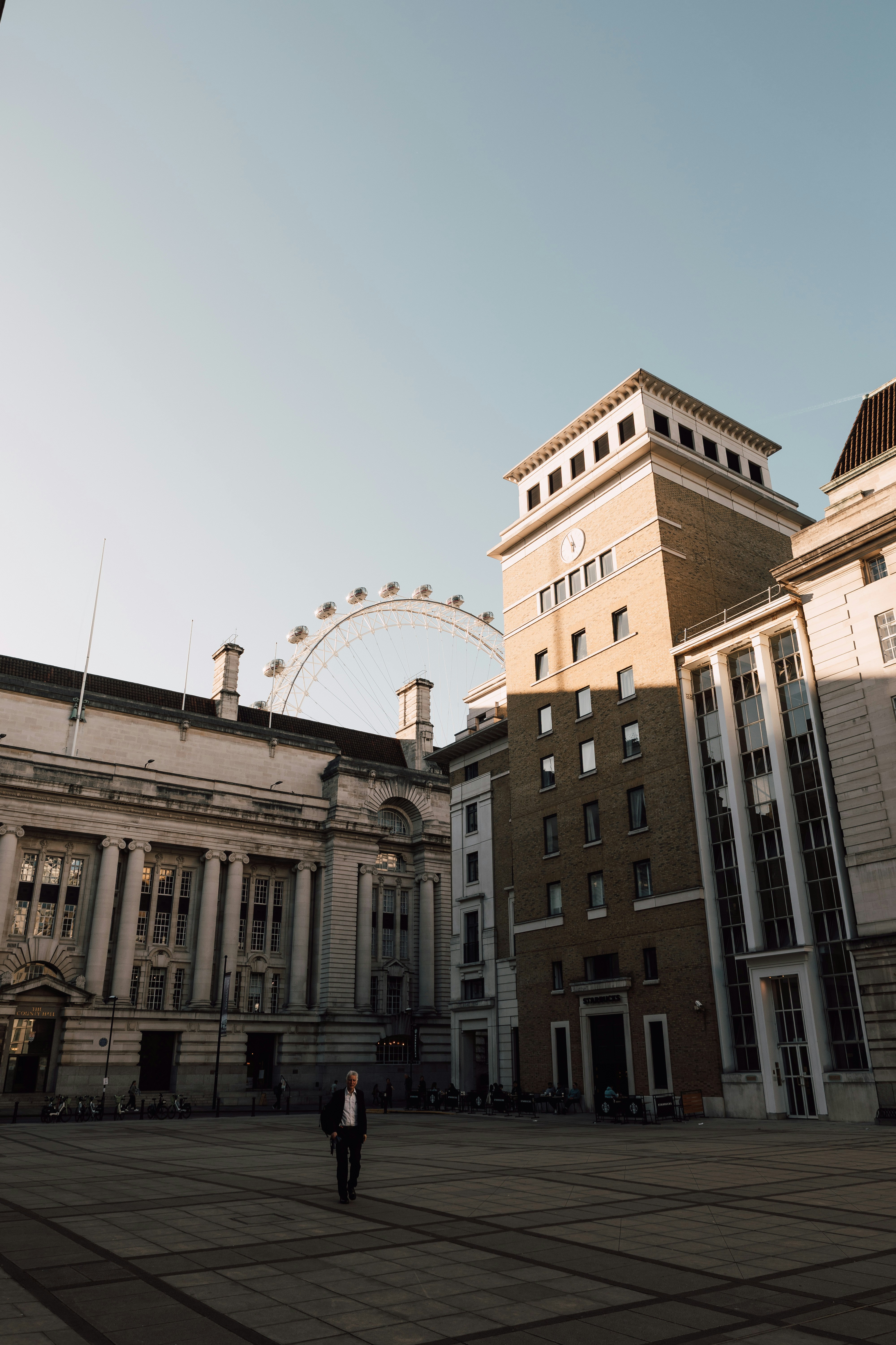 Man walks in a city square with famous structures.