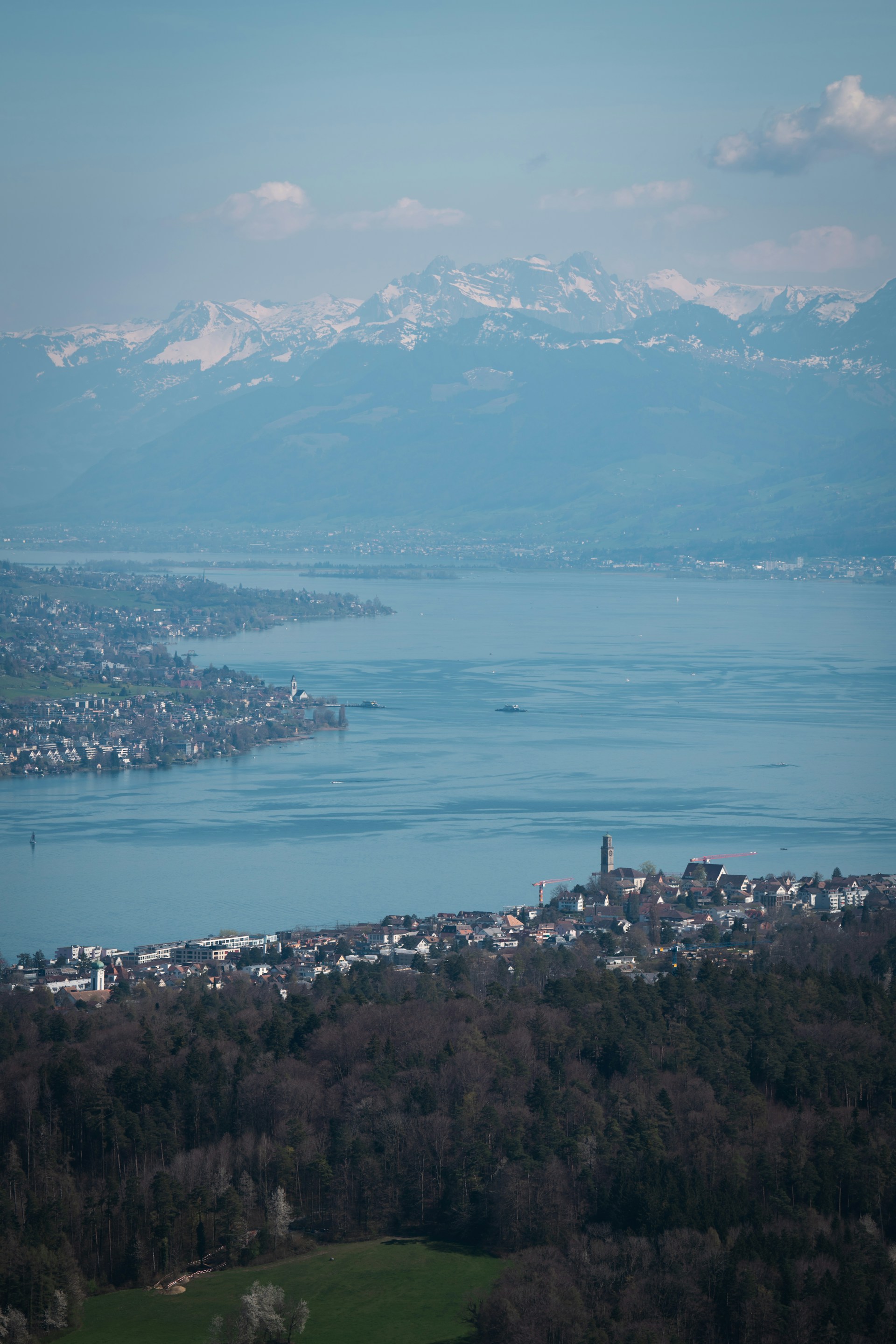A lake flows alongside a town and mountains.