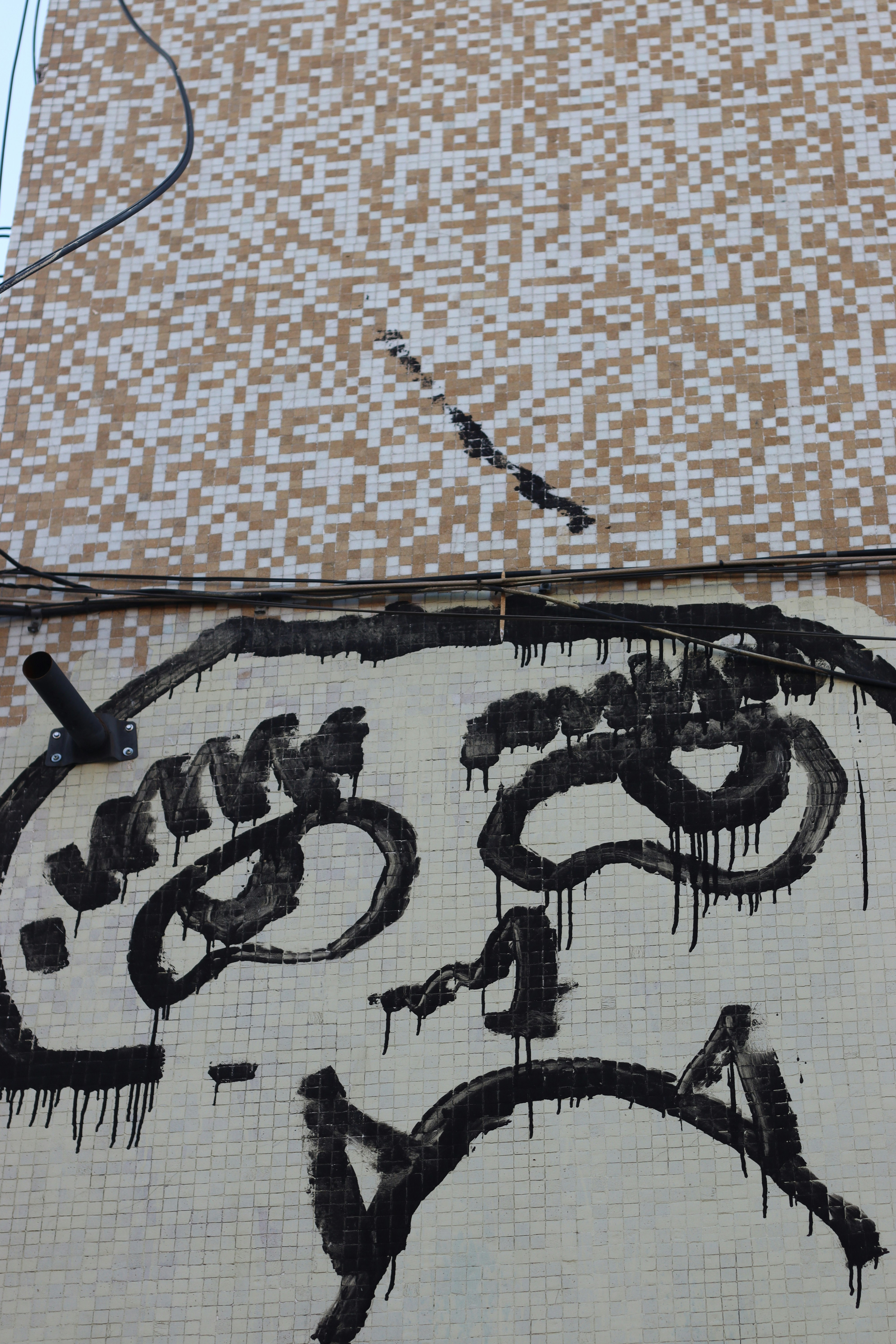 Graffiti face painted on a tile wall.