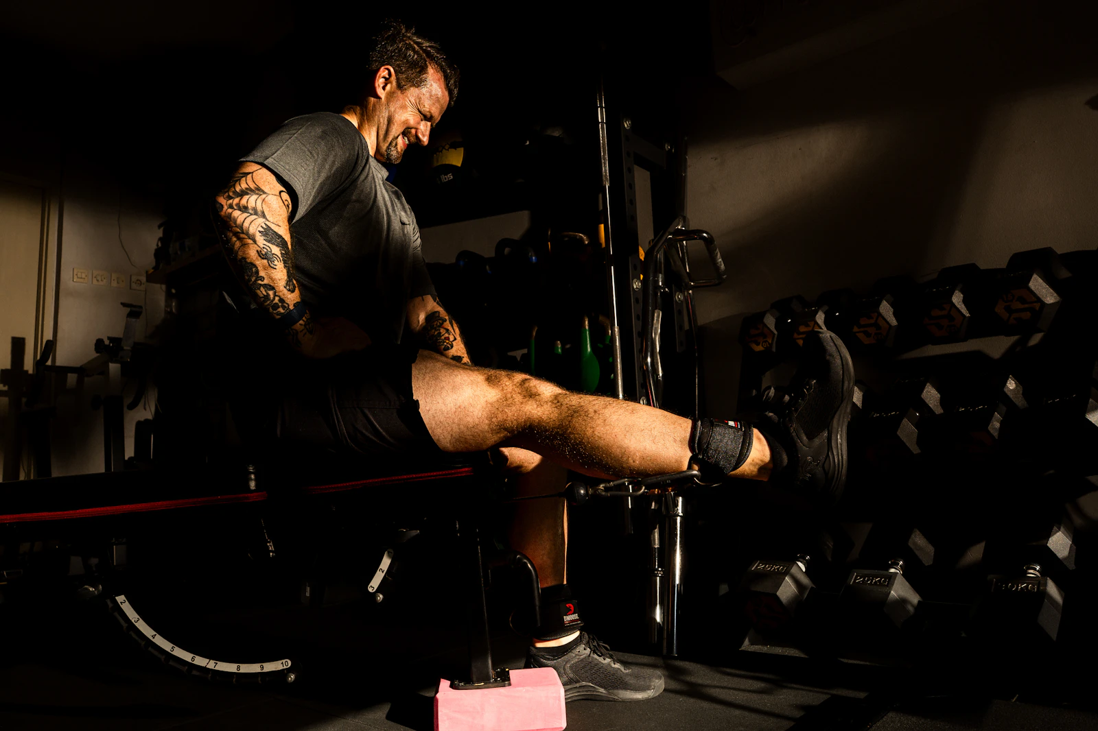 Athlete performing a loaded leg extension during strength testing in a rehab gym