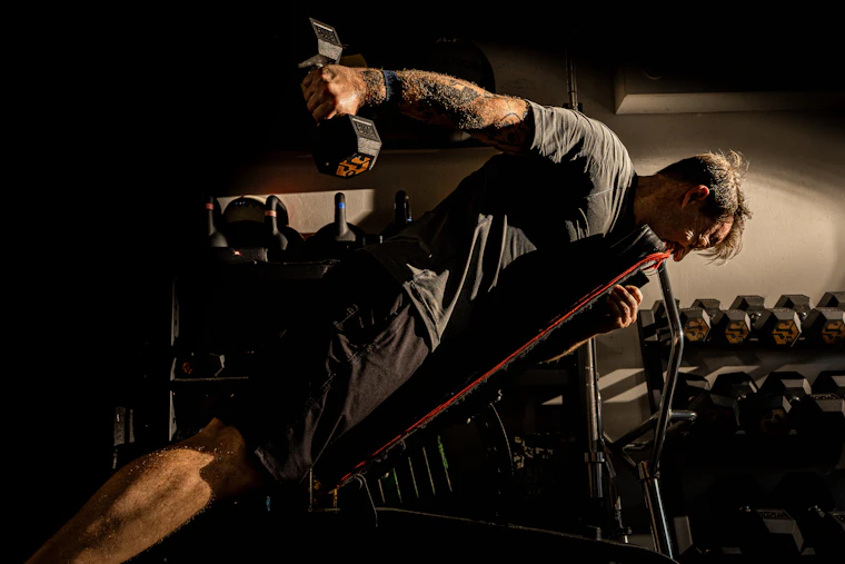 Hombre canoso entrenando con mancuernas en un gimnasio
