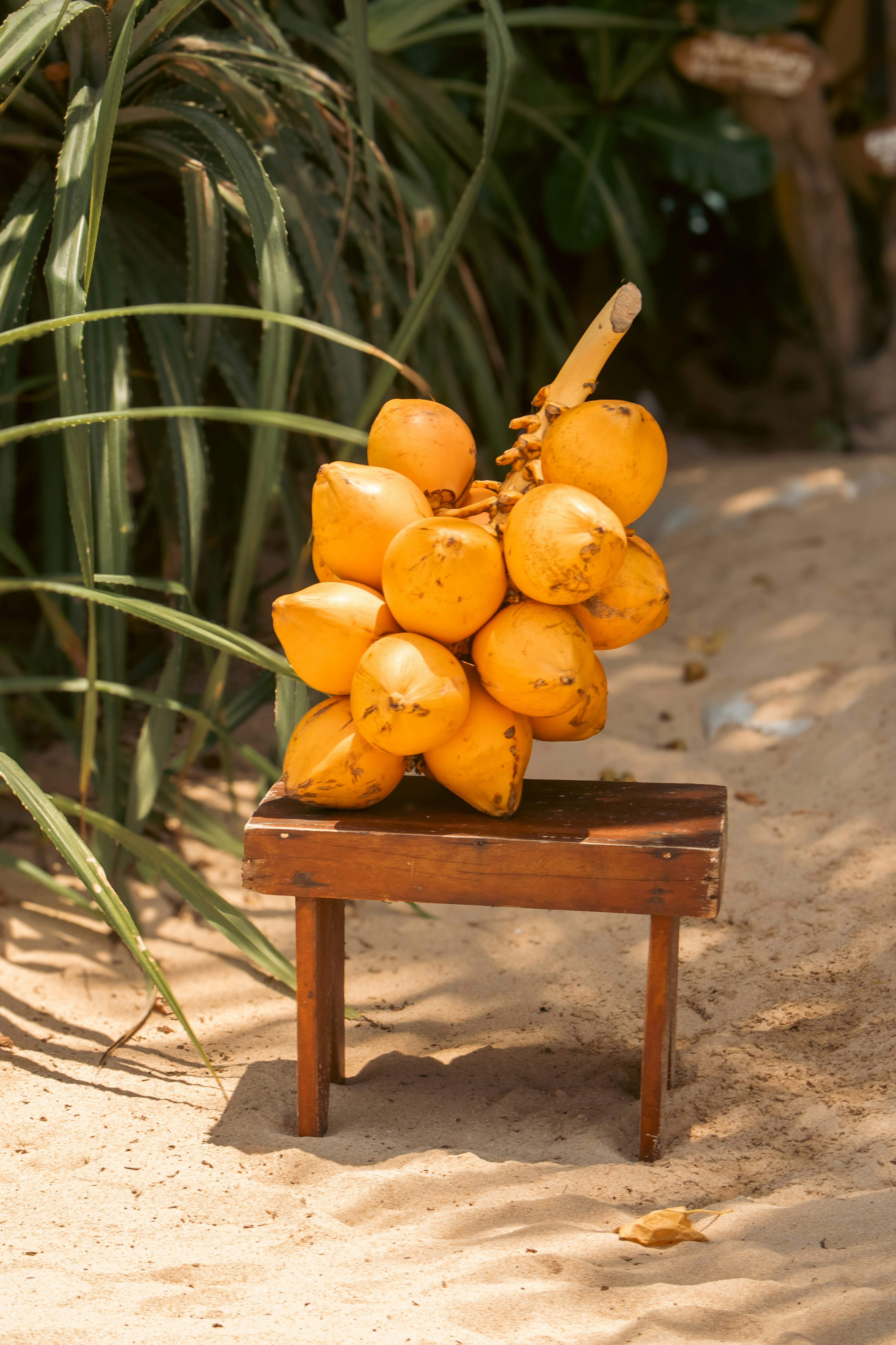 A bunch of yellow coconuts sits on a wooden stool.
