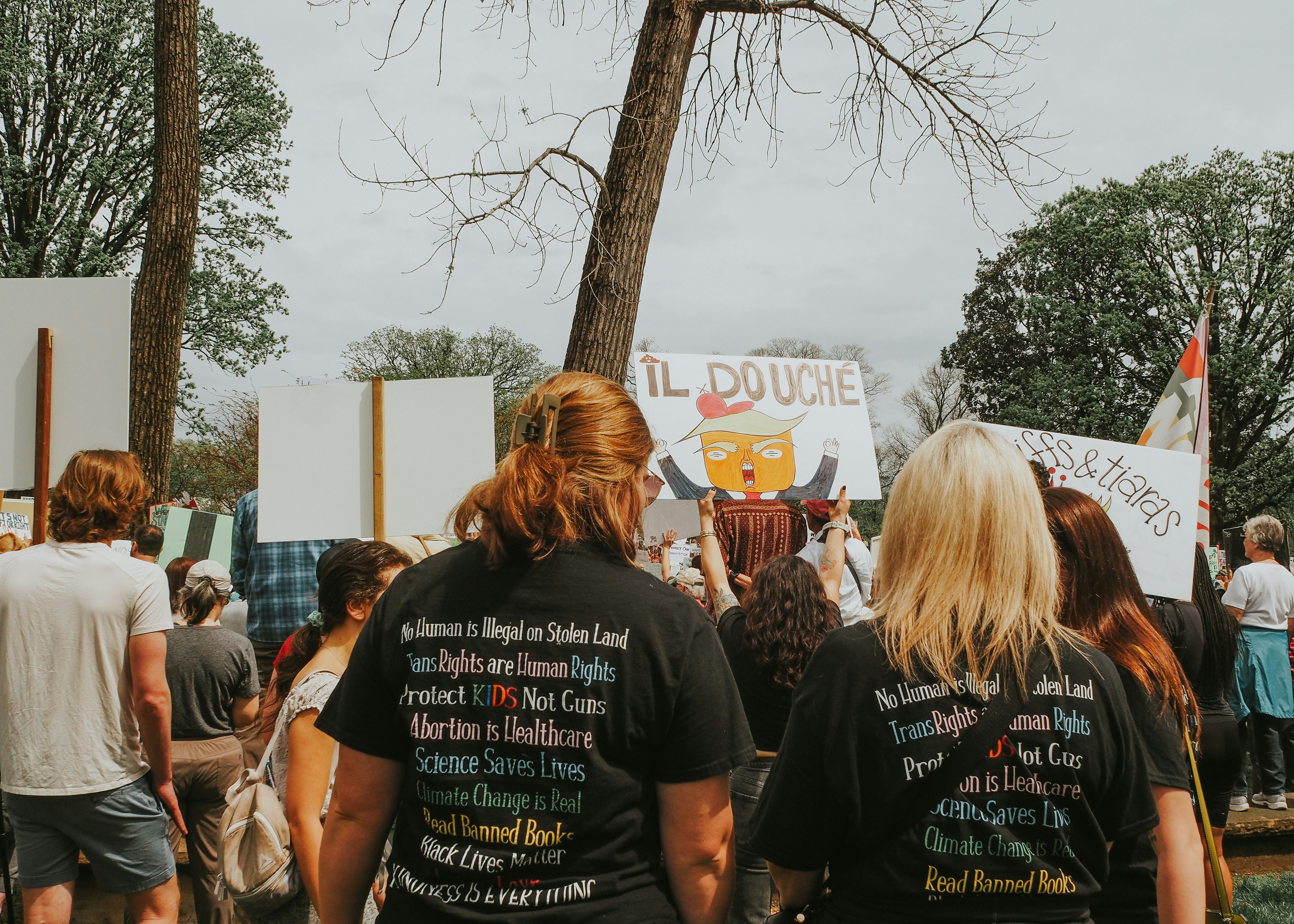 People protest with signs, likely at a rally.