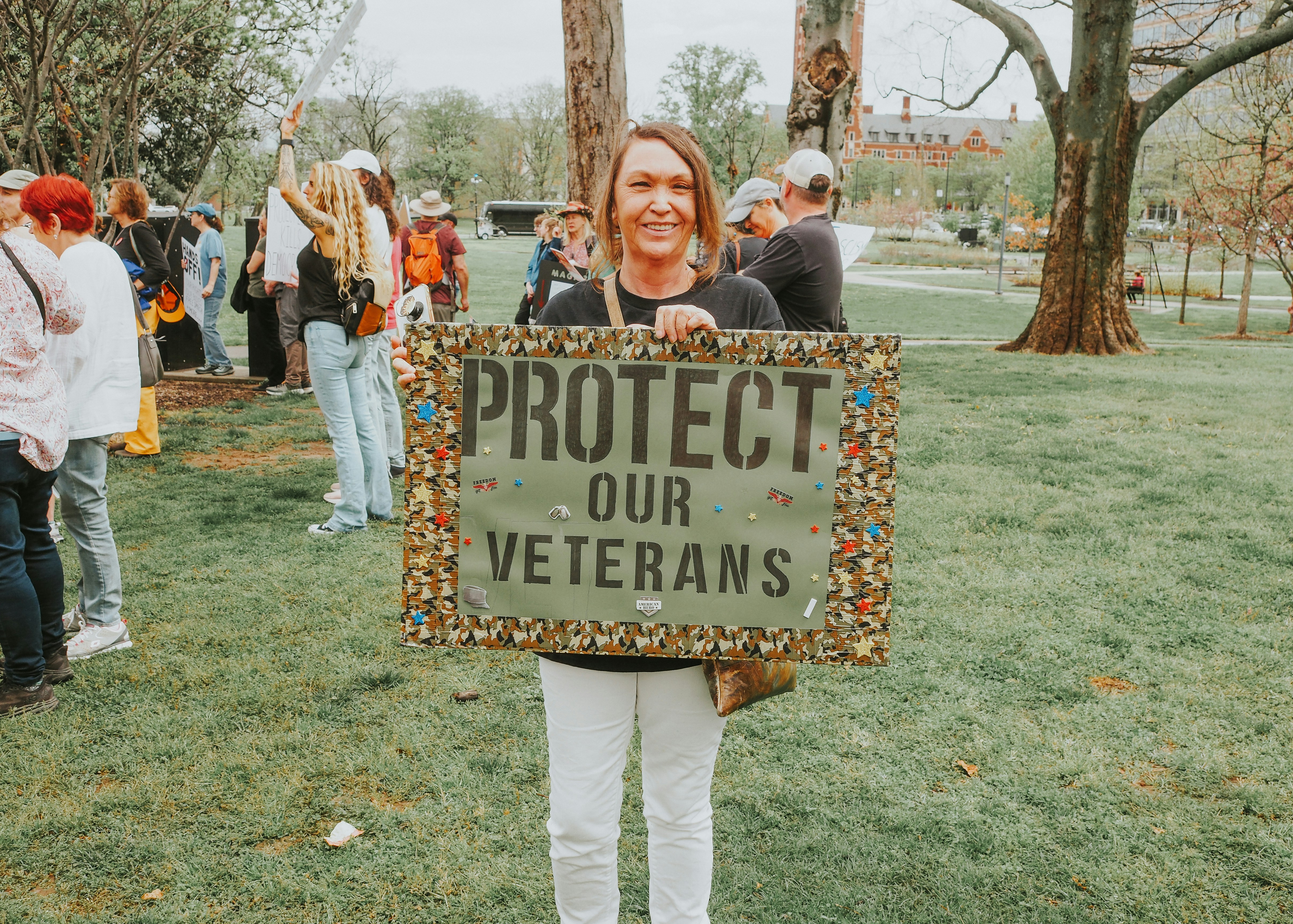 Woman protests to protect veterans with sign.