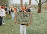 Woman protests to protect veterans with sign.